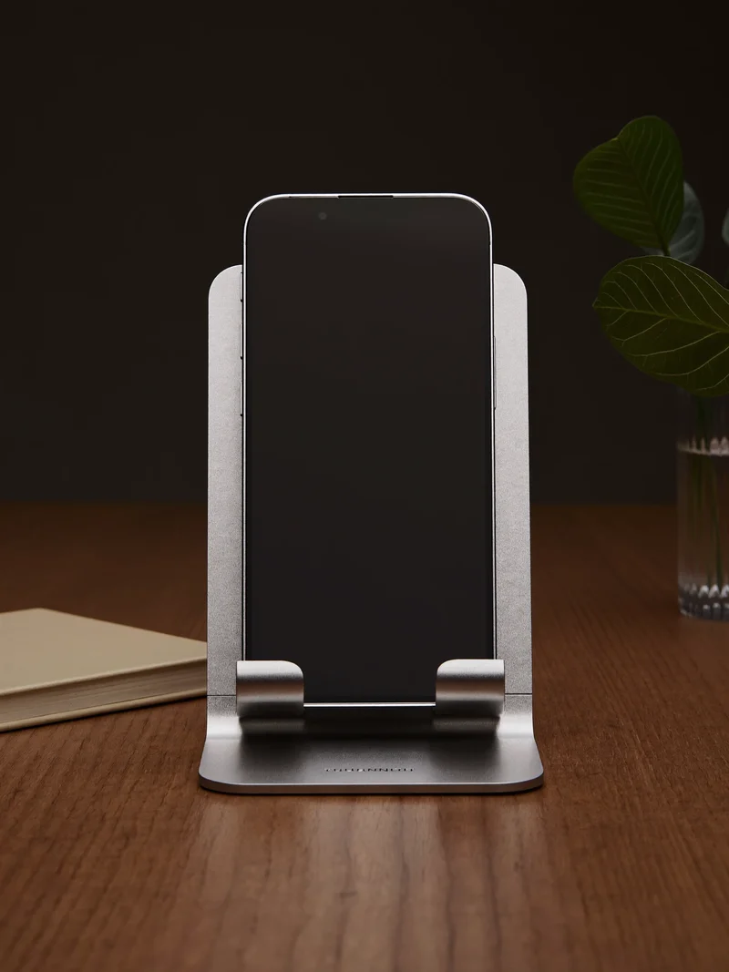 Suport din aluminiu periat pe un birou ordonat, cu un telefon cu ecran stins